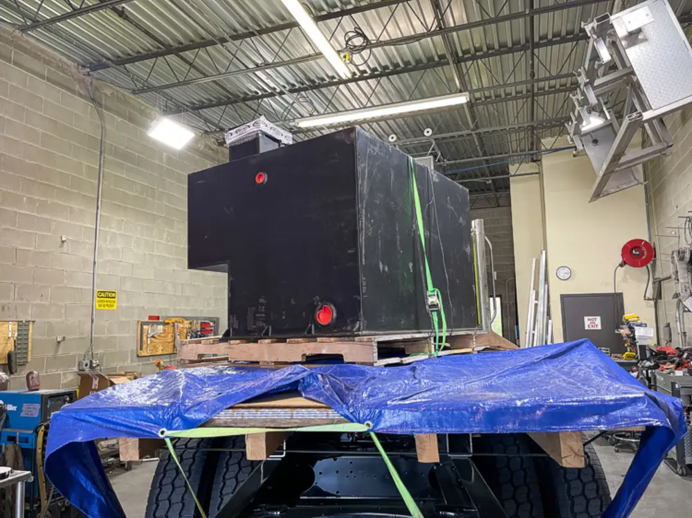 Exterior view of small fire truck showing cab, body compartments, and wheel/tire area.